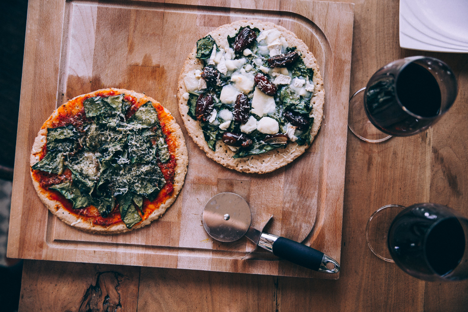 Två pizzor på skärbräda med vin